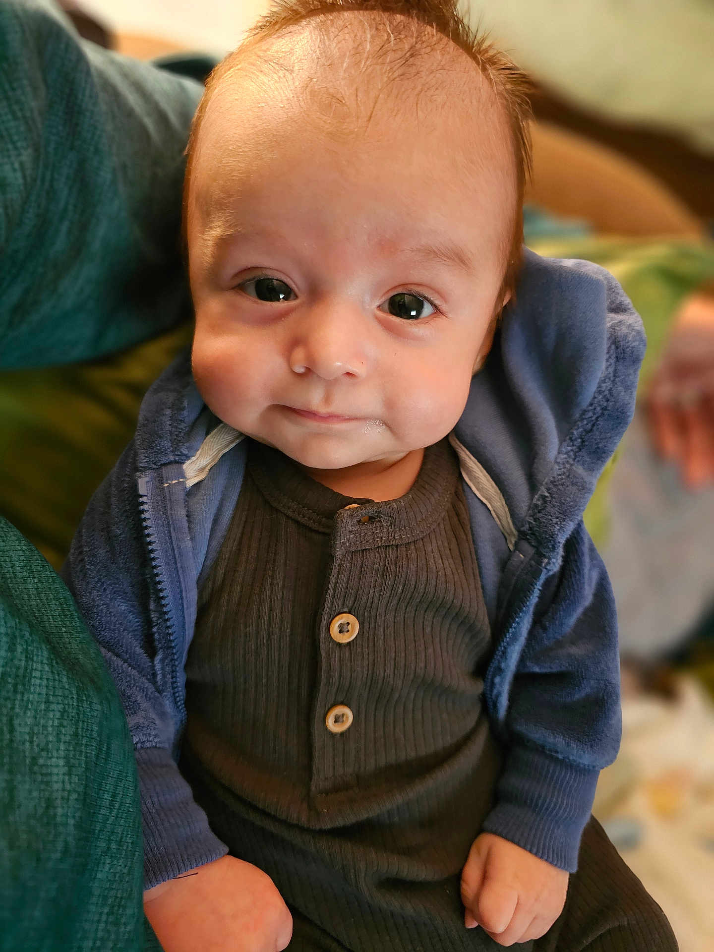 Avery joined the competition — help win amazing prizes! baby, child, face, eyes, smile, hoodie, clothing, infant, portrait, cute, sitting, indoors, hand, young, cozy, expression, person, warm, soft_light, background_blur