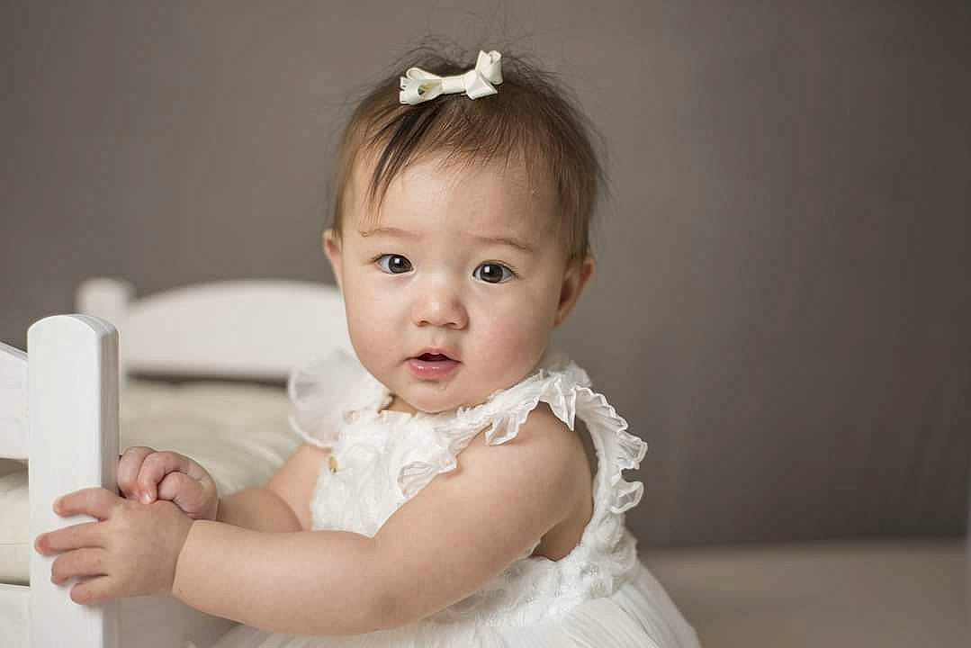 Saya is registered to the contest to win money with this photo: baby, baby_toddler_clothing, bridal_accessory, cheek, chin, dress, embellishment, eye, eyebrow, eyelash, flash_photography, gesture, hair, happy, head, headpiece, iris, lip, person, sleeve