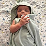 baby, blanket, child, comfort, cozy, cute, face, hand, hooded_towel, indoors, infant, lying_down, newborn, patterned_blanket, peaceful, skin, small_hands, soft_texture, towel, wrapped