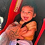 Josiah joined the competition — help win amazing prizes! baby, child, car_seat, smiling, tattoo, hand, pacifier, blanket, clothing, infant, seatbelt, red, black, yellow, cute, happy, portrait, closeup, person, sitting