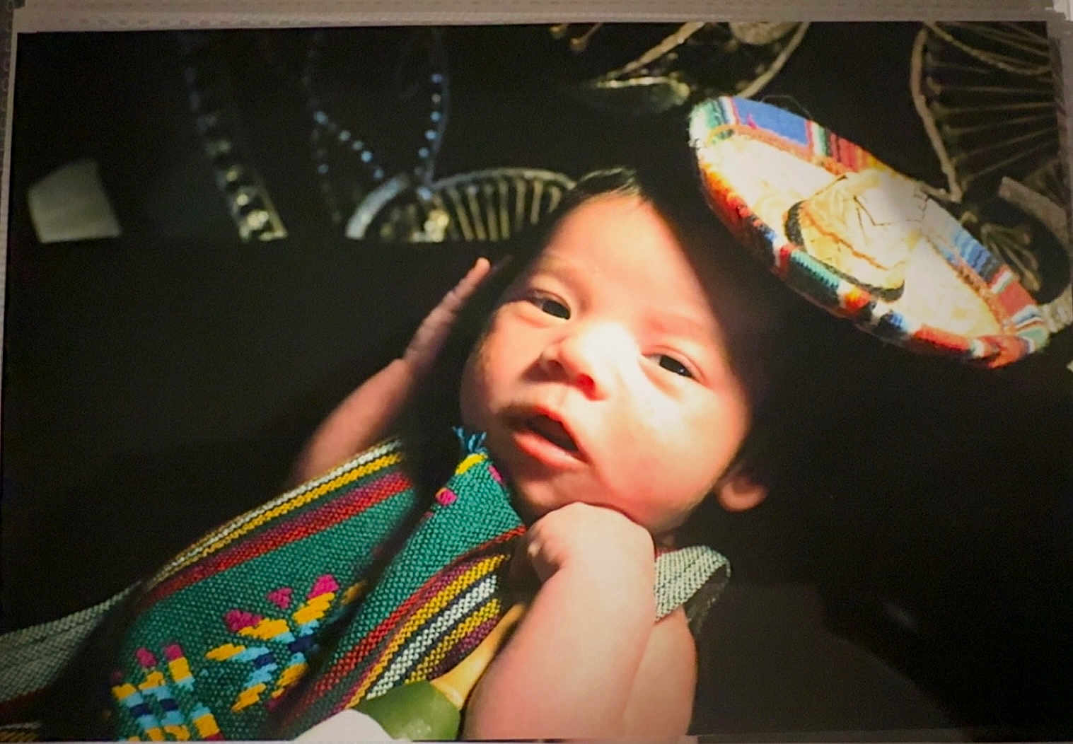 Josiah is registered to the contest to win money with this photo: baby, infant, face, hat, colorful_clothing, woven_fabric, hand, portrait, newborn, closeup, soft_light, dark_background, cute, child, skin, expression, person, headwear, young, indoors