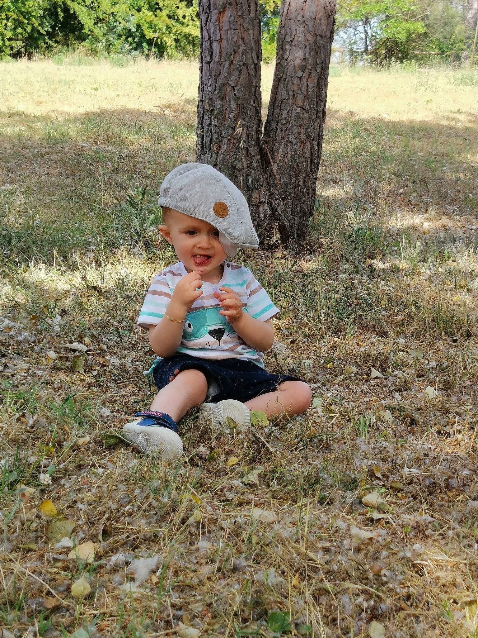 Tyno participe au concours pour gagner de l'argent avec cette photo : baby, baby_toddler_clothing, cap, child, fun, grass, grass_family, grassland, groundcover, happy, hat, headwear, landscape, leisure, people_in_nature, person, plant, sitting, soil, sun_hat