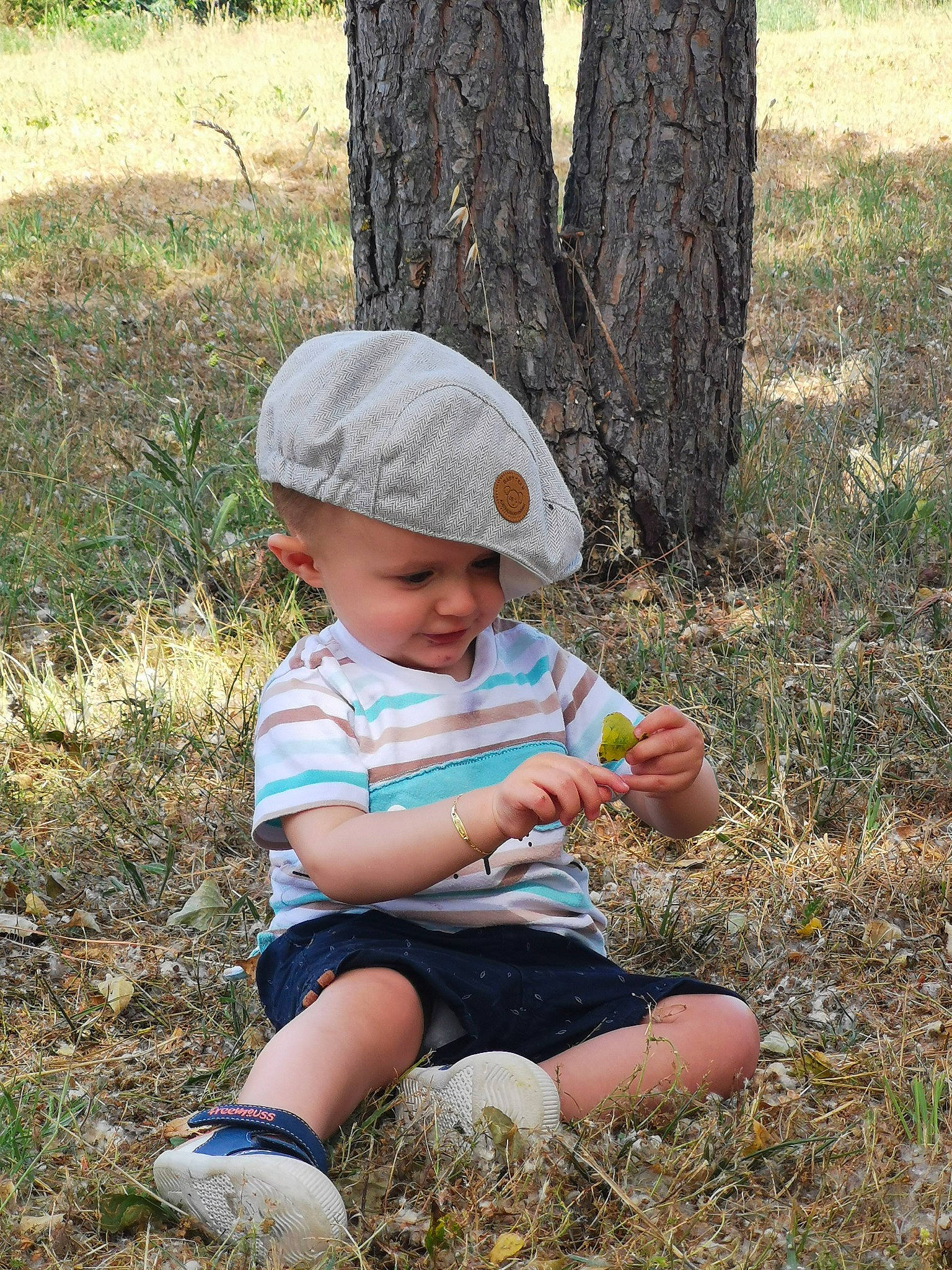 Tyno participe au concours pour gagner de l'argent avec cette photo : baby, baby_toddler_clothing, baseball_cap, botany, cap, child, fun, grass, grass_family, grassland, hat, headwear, leaf, people_in_nature, person, plant, sitting, soil, sun_hat, toddler