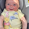 baby, car_seat, onesie, winnie_the_pooh, piglet, yellow_clothing, smile, happy, infant, child, sunlight, seatbelt_warning_label, cute, portrait, skin, hand, legs, face, person, indoor