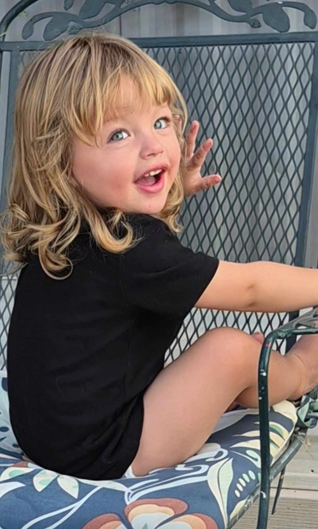 Oziah is registered to the contest to win money with this photo: black_shirt, blonde_hair, casual_clothing, chair, child, curly_hair, cushion, cute, expression, face, happy, metal_chair, outdoor, pattern, playful, portrait, seated, smiling, toddler, young