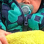 child, baby, pacifier, jacket, winter_clothing, blanket, hand, face, closeup, cozy, warm, outdoor, hood, fabric, texture, infant, clothing, person, portrait, young