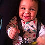 baby, child, car_seat, smiling, dinosaur_print, onesie, happy, infant, hand, toy, seatbelt, cute, face, young_child, straps, cheeks, motion_blur, indoor, person, portrait
