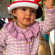 Iris participe au concours pour gagner de l'argent avec cette photo : toddler, child, hat, pom_poms, purple_cardigan, remote_control, indoor, waving, tongue_out, cute, smiling, person, young_child, buttoned_cardigan, wooden_floor, home_interior, furniture, playful, portrait, face