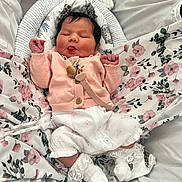 Aurora-Mai is registered to the contest to win money with this photo: baby, sleeping, tongue_out, pink_cardigan, white_socks, lace, floral_blanket, baby_nest, infant, cute, newborn, cozy, soft, indoors, child, peaceful, resting, clothing, portrait, adorable