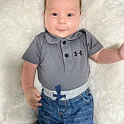 Ethan joined the competition — help win amazing prizes! baby, infant, child, smiling, face, polo_shirt, jeans, clothing, lying_down, blanket, soft_texture, cute, happy, portrait, person, skin, head, expression, casual_wear, indoor