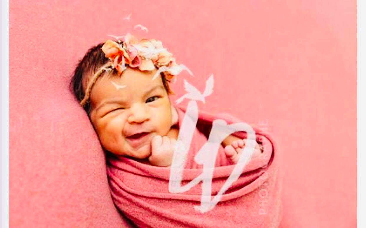 Léanah participe au concours pour gagner de l'argent avec cette photo : arm, baby, cheek, eyelash, flower, gesture, happy, headband, headpiece, headwear, jewellery, lip, magenta, nail, neck, person, petal, pink, plant, smile