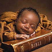Akylo joined the competition — help win amazing prizes! baby, sleeping, bible, brown_blanket, smile, infant, peaceful, portrait, cozy, soft_lighting, closeup, hands, curly_hair, resting, warm_colors, indoors, religion, book, child, cute