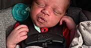 Akylo is registered to the contest to win money with this photo: baby, blanket, car_seat, child, closeup, clothing, comfort, cute, face, hand, indoor, infant, newborn, pacifier, peaceful, portrait, rest, safety, sleeping, soft