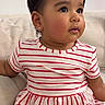 toddler, child, dress, striped_clothing, sitting, couch, indoors, curly_hair, earring, cute, portrait, baby, young_child, comfortable, soft_furniture, looking_away, innocent, happy, small_shoes, casual