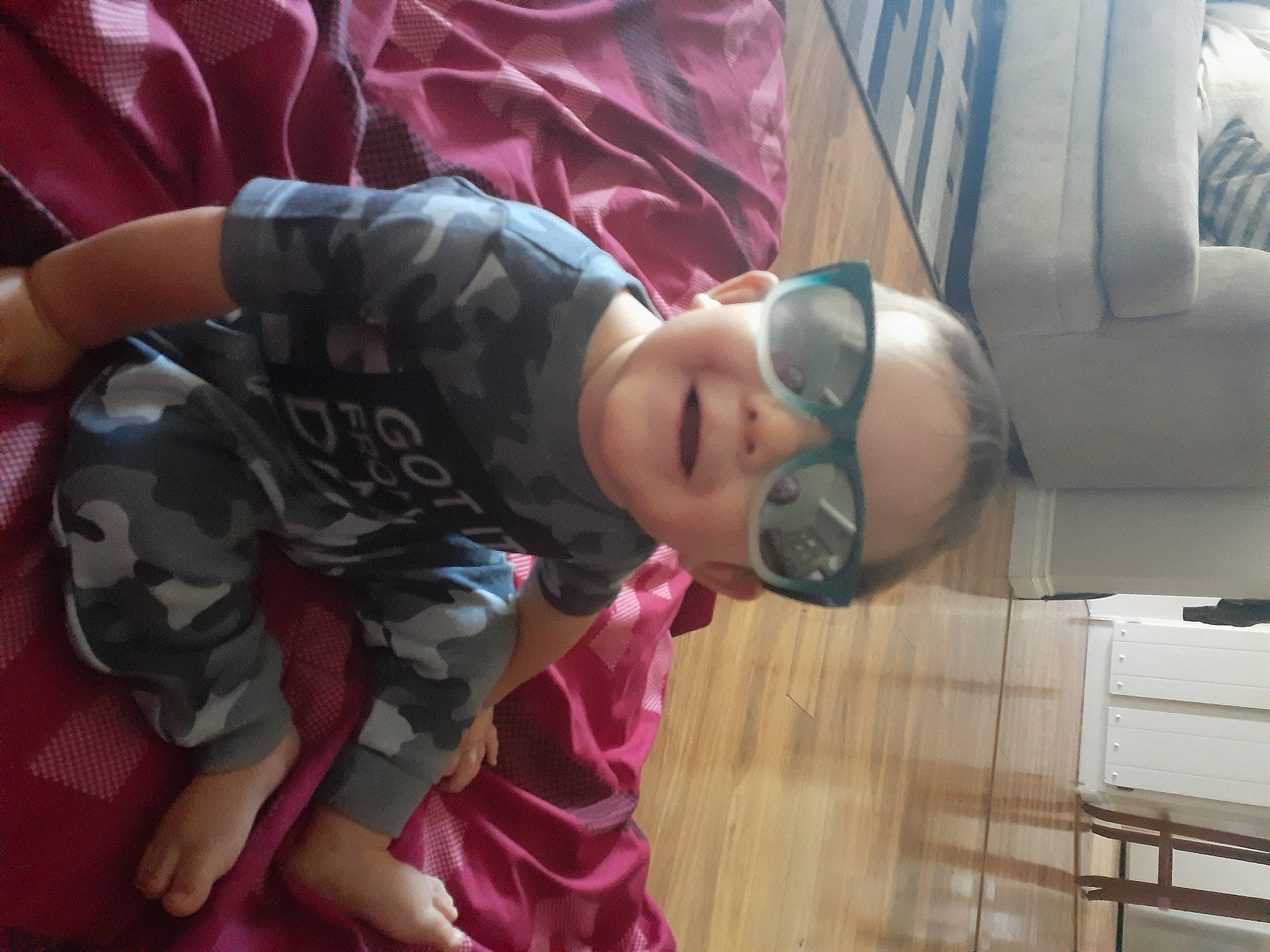 Noah is registered to the contest to win money with this photo: car_seat, child, comfort, eyewear, flooring, fun, glasses, leisure, magenta, pattern, person, purple, room, sitting, sunglasses, t_shirt, thigh, toddler, vacation, vehicle_door