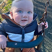 Oscar joined the competition — help win amazing prizes! child, toddler, swing, playground, chain, jacket, outdoor, daylight, happy, blue_eyes, blond_hair, smile, cute, baby, seat, metal, park, grass, fence, person
