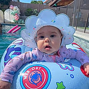 Raven is registered to the contest to win money with this photo: baby, pool, float_ring, sun_hat, water, swimming_pool, outdoor, child, inflatable, summer, balloons, pink, blue, sleepsuit, fence, sky, fun, floating, cute, sunny
