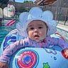 baby, pool, float_ring, sun_hat, water, swimming_pool, outdoor, child, inflatable, summer, balloons, pink, blue, sleepsuit, fence, sky, fun, floating, cute, sunny