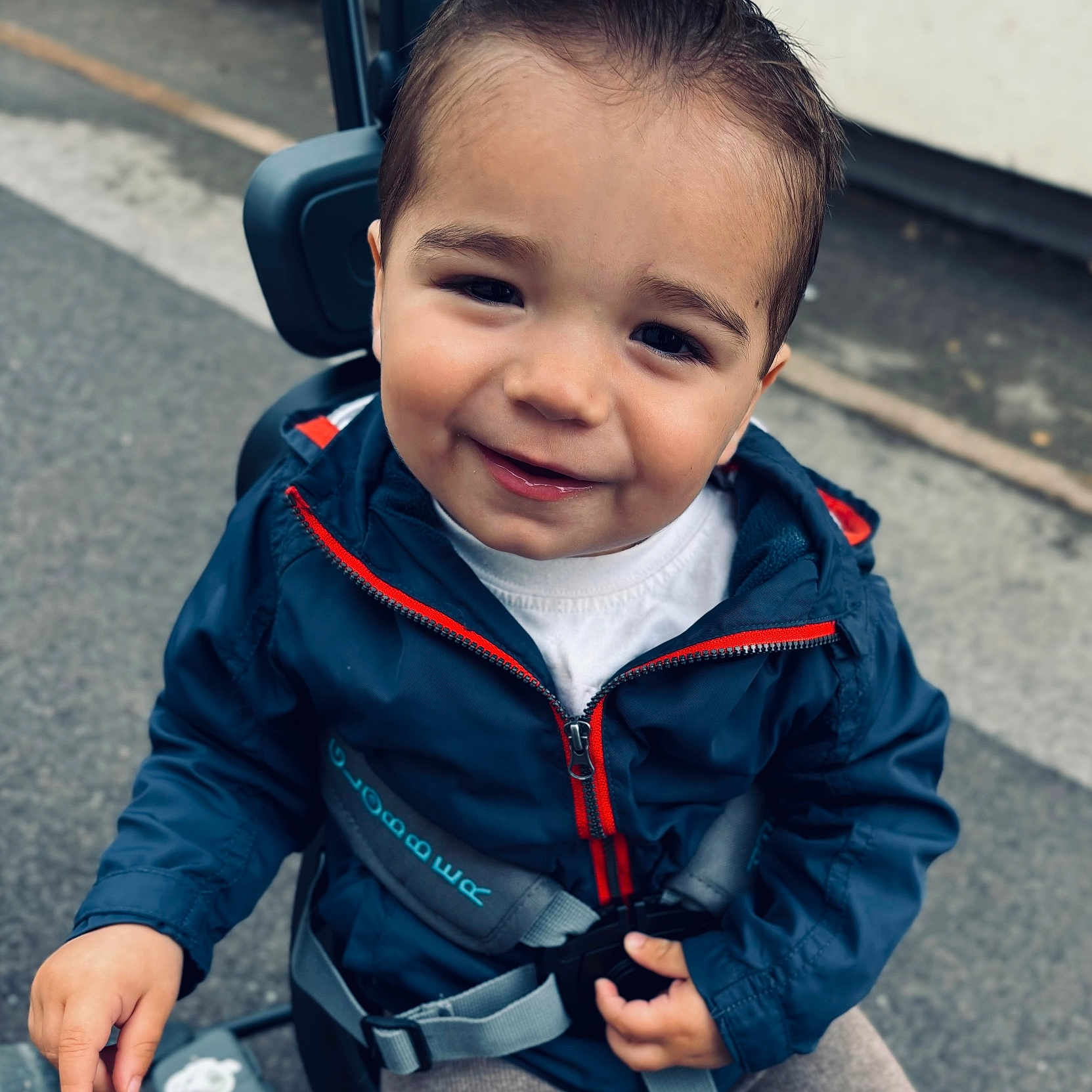 Enzo a rejoint le concours — aidez-le/la à gagner de superbes lots ! accessories, baby, babylaughing, city, clothing, coat, face, happy, head, jacket, pants, person, photography, portrait, road, sitting, smile, strap, street, urban