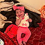 baby, child, pink_clothing, headband, bow, smiling, finger_in_mouth, blanket, bed, red_bedspread, happy, indoor, cute, infant, toddler, cozy, person, soft_toys, relaxed, playful
