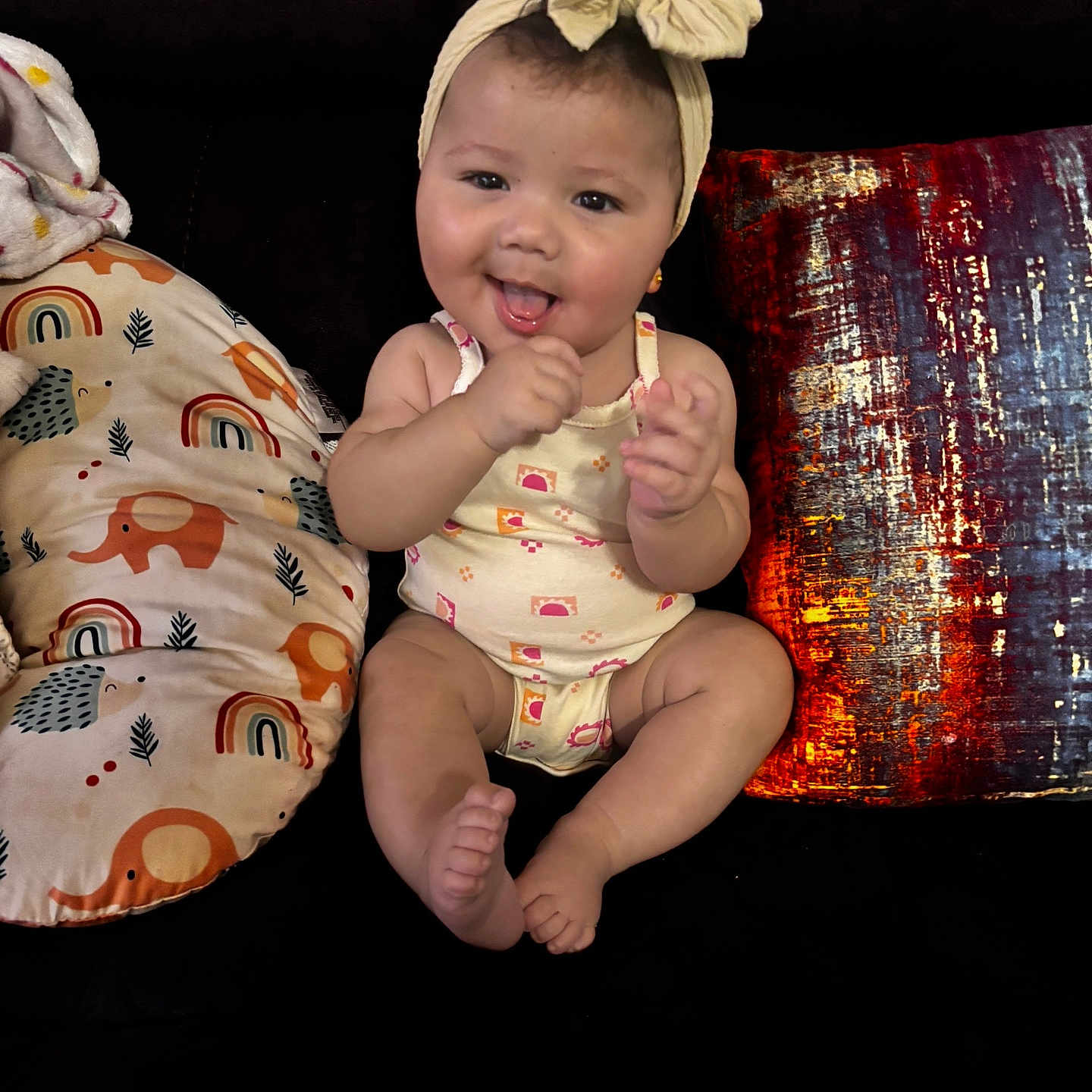 Armoni joined the competition — help win amazing prizes! baby, bow, child, clothing, colorful, couch, cute, face, furniture, happy, headband, indoors, infant, pattern, person, pillow, sitting, skin, smiling, tongue_out