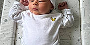 Albie is registered to the contest to win money with this photo: baby, infant, white_hat, white_shirt, grey_pants, changing_pad, animal_pattern, stars, clouds, giraffe, elephant, sleepwear, newborn, arms_up, lying_down, soft_lighting, indoors, cute, peaceful, child