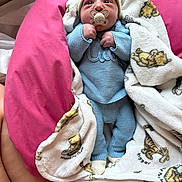 Maïden participe au concours pour gagner de l'argent avec cette photo : baby, pacifier, blanket, winnie_the_pooh, knitwear, hat, blue_clothing, beige_hat, infant, cozy, cute, pink_cushion, wrapped, hand, sleepwear, soft_toy_pattern, newborn, indoors, portrait, person