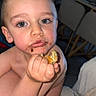 toddler, child, snack, messy_face, indoor, chair, pacifier, blue_eyes, skin, hand, food, expression, unfocused_background, hair, person, young_child, curious, close_up, bite, candid