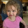 toddler, child, messy, food, curly_hair, pink_shirt, kitchen, indoor, smile, face, person, young_child, cabinet, countertop, adult, background, candid, happy, cute, portrait
