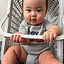 baby, child, laundry_basket, grey_onesie, drool, hands, legs, bedroom, door, curious, cute, chubby_cheeks, sitting, indoor, plastic, furniture, floor, expression, person, infant