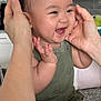 Bosco is registered to the contest to win money with this photo: baby, child, smiling, happy, hands, green_clothing, indoor, kitchen, face, infant, cute, joyful, sitting, person, skin, short_hair, human, portrait, closeup, expression