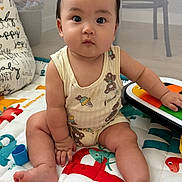 Bosco is registered to the contest to win money with this photo: baby, child, infant, playmat, toy, colorful, dinosaur, sitting, cute, curious, indoors, mesh, clothing, foot, hand, face, expression, playpen, pillow, soft