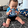 Bosco joined the competition — help win amazing prizes! baby, child, blue_shirt, sippy_cup, bedspread, indoor, furniture, pillow, foot, hand, face, expression, concentration, home, floor, door, closet, black_shorts, toy, infant
