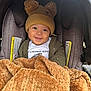 baby, blanket, car_seat, child, closeup, cozy, cute, face, happy, hat, headwear, indoors, infant, jacket, person, portrait, seatbelt, smile, snuggled, warm_clothing