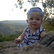 Léonïa a rejoint le concours — aidez-le/la à gagner de superbes lots ! baby, child, face, portrait, outdoor, nature, rock, hat, striped_clothing, smile, curious, person, headwear, forest, background, young_child, daylight, cute, exploration, scenic