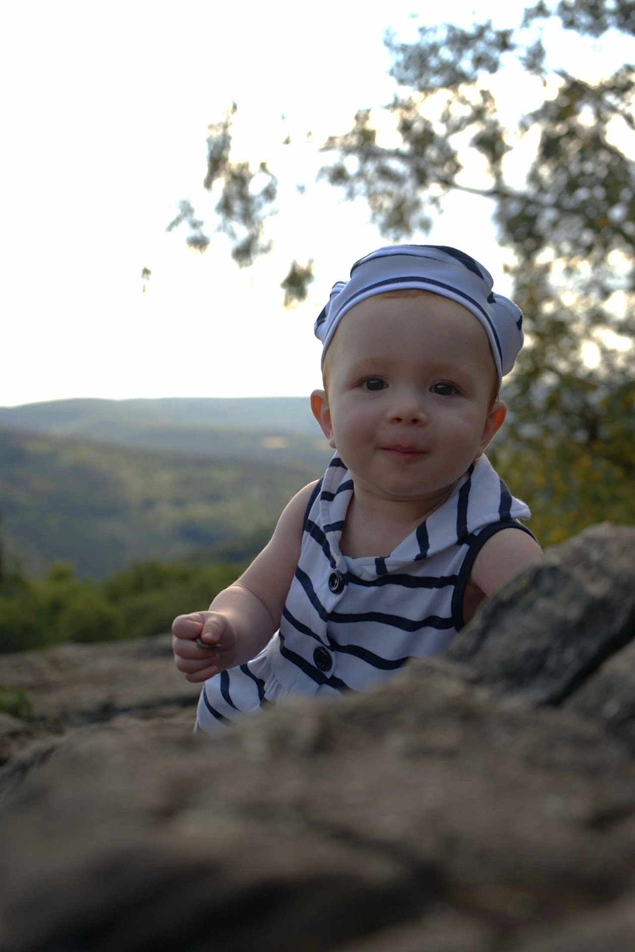 Léonïa a rejoint le concours — aidez-le/la à gagner de superbes lots ! baby, child, face, portrait, outdoor, nature, rock, hat, striped_clothing, smile, curious, person, headwear, forest, background, young_child, daylight, cute, exploration, scenic