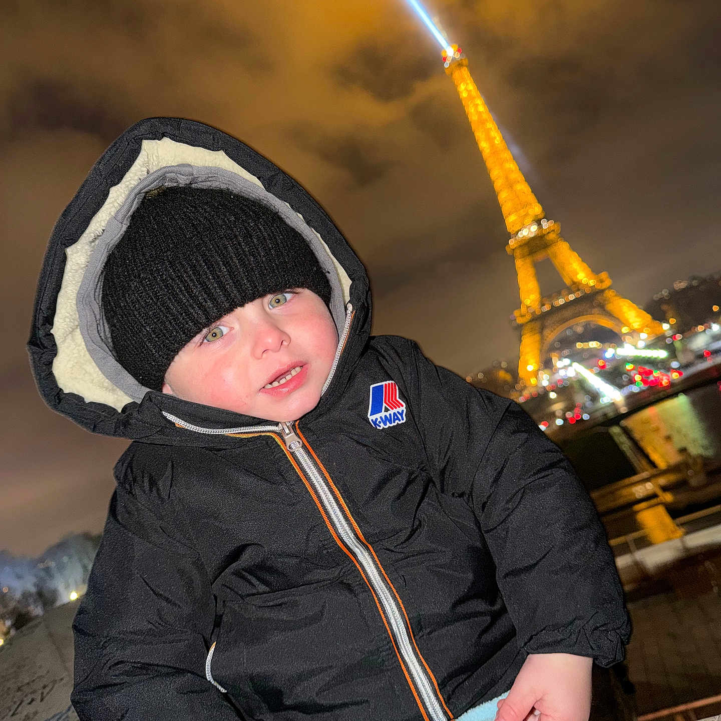 Deyton participe au concours pour gagner de l'argent avec cette photo : beanie, cheeks, child, cityscape, coat, eiffel_tower, face, hat, hood, k_way, landmark, lights, night, railing, river, smile, toddler, tourist, winter, zipped_jacket
