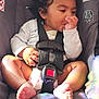 Gabriel is registered to the contest to win money with this photo: toddler, child, car_seat, curly_hair, thumb_sucking, diaper, safety_harness, seatbelt, infant, baby, clothing, foot, hand, indoors, soft_light, colorful_reflections, comfort, sitting, portrait, cute