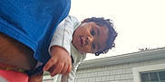 Gabriel joined the competition — help win amazing prizes! baby, child, curly_hair, face, hand, outdoor, house, window, building, sky, person, portrait, clothing, blue_shirt, red_garment, young_child, looking_at_camera, close_up, daylight, casual