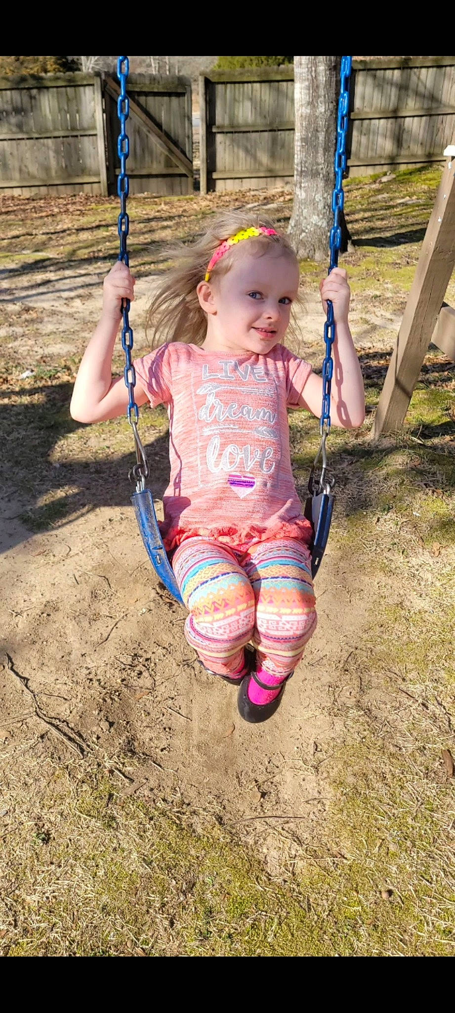 Lilly is registered to the contest to win money with this photo: baby_toddler_clothing, child, electric_blue, foot, fun, grass, happy, human_leg, joy, knee, leisure, outdoor_play_equipment, people_in_nature, person, playground, recreation, sand, smile, swing, t_shirt