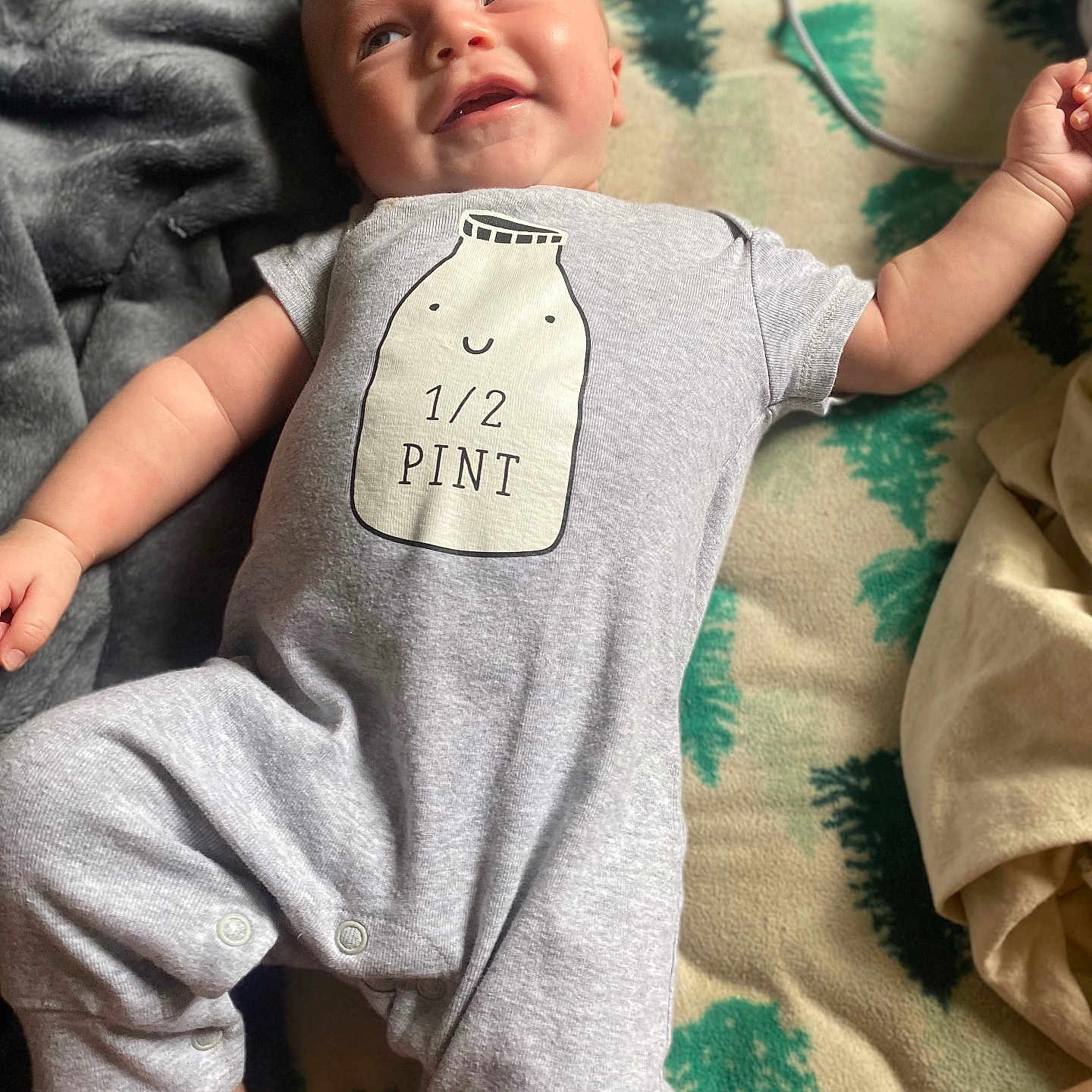 Simon joined the competition — help win amazing prizes! arm, baby, blanket, child, clothing, cozy, cute, face, foot, happy, head, indoor, infant, laying_down, onesie, person, portrait, relaxed, smiling, soft_texture