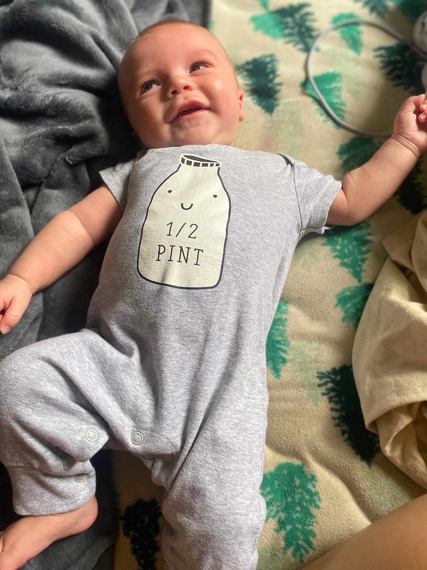 Simon joined the competition — help win amazing prizes! baby, infant, smiling, onesie, clothing, blanket, laying_down, cute, happy, face, head, arm, foot, soft_texture, indoor, child, person, portrait, cozy, relaxed