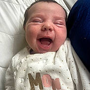 Lexya a rejoint le concours — aidez-le/la à gagner de superbes lots ! baby, cheeks, close_up, cozy, dark_hair, face, gummy_smile, happy, indoor, infant, mouth_open, newborn, onesie, pillow, polka_dots, portrait, printed_text, quilted_mattress, smiling, white_background