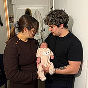 Lexya a rejoint le concours — aidez-le/la à gagner de superbes lots ! baby, woman, man, indoor, family, holding, sleeping, onesie, clothing, tattoo, hair, door, coat, love, parenthood, people, portrait, warm_lighting, cute, intimate