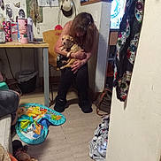 Molbery is registered to the contest to win money with this photo: baby_play_mat, blanket, casual, chair, clothing, decorations, dog, floor, hat, home, hugging, indoor, patterned_cloth, pet, plant, sitting, table, television, wall, woman