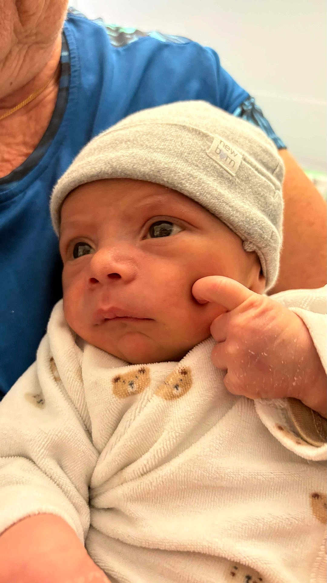 Gabriel a rejoint le concours — aidez-le/la à gagner de superbes lots ! newborn, baby, infant, hat, onesie, teddy_bear, hand, face, adult, holding, blue_shirt, skin, expression, cute, indoor, portrait, clothing, person, closeup, newborn_baby