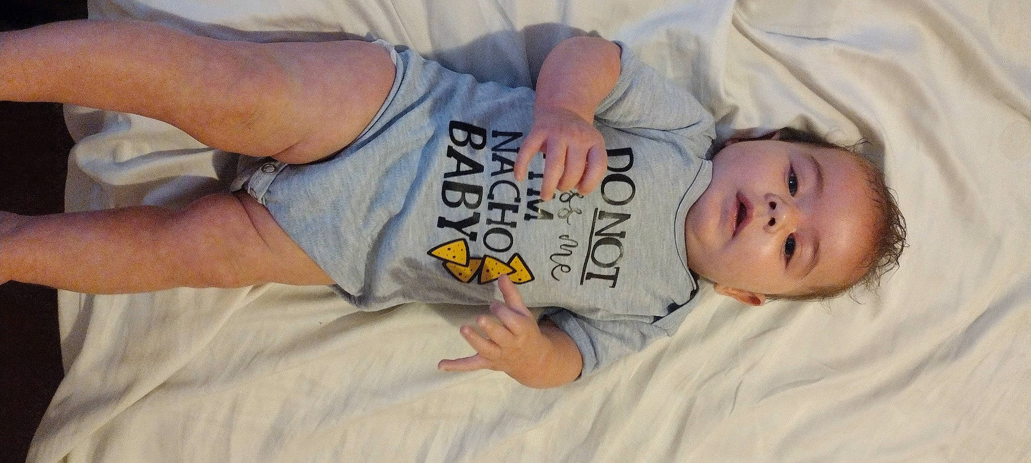 Daxton is registered to the contest to win money with this photo: baby, baby_toddler_clothing, bedtime, cheek, child, comfort, elbow, eye, gesture, hand, happy, human_body, linens, mouth, nose, person, sitting, sleep, sleeve, t_shirt