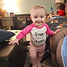baby, blanket, child, clock, couch, family, furniture, home, indoor, lamp, living_room, long_sleeves, pink_clothing, portrait, siblings, smiling, standing, tablet, toddler, walking