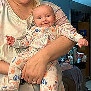 Rylee joined the competition — help win amazing prizes! baby, smiling, infant, pajamas, colorful_clothing, person, adult_hand, indoor, room, furniture, bed, blanket, holding, portrait, cute, happy, face, skin, arm, casual_clothing