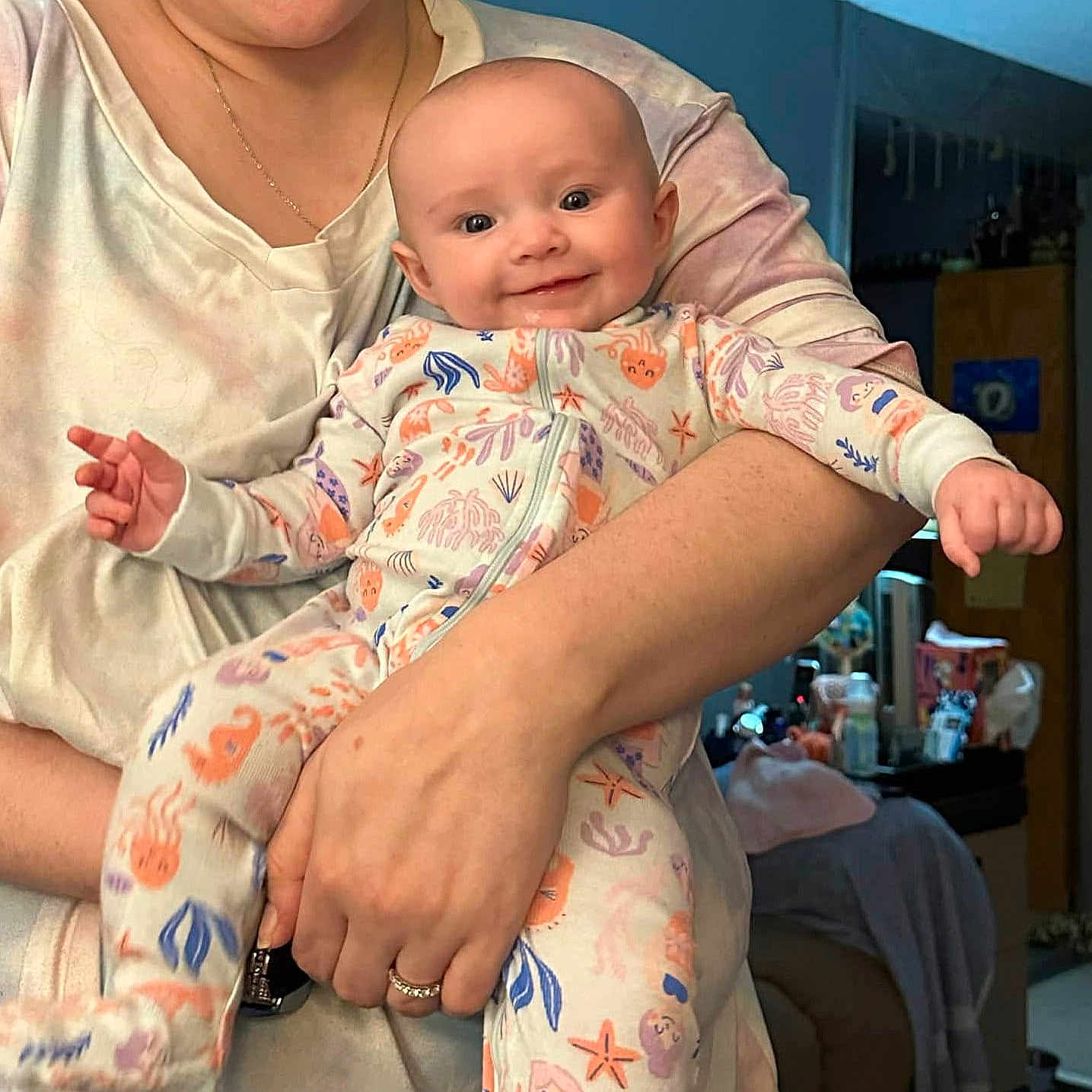 Rylee joined the competition — help win amazing prizes! baby, smiling, infant, pajamas, colorful_clothing, person, adult_hand, indoor, room, furniture, bed, blanket, holding, portrait, cute, happy, face, skin, arm, casual_clothing